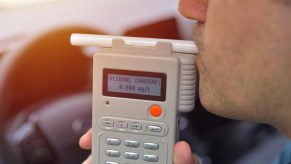 A male driver taking a breathalyzer test to check for possible DUI in close view