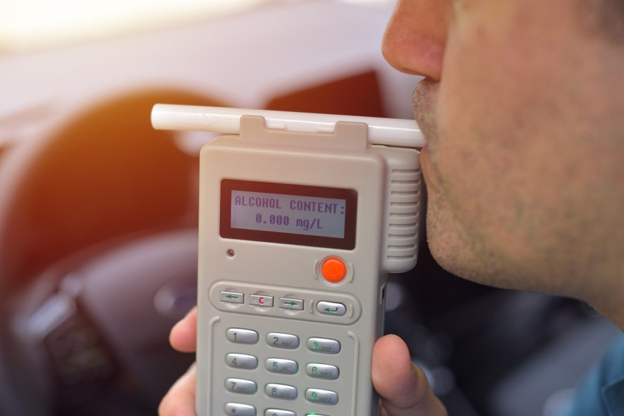 A male driver taking a breathalyzer test to check for possible DUI in close view
