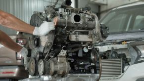 A mechanic raising and lowering the engine out of a car
