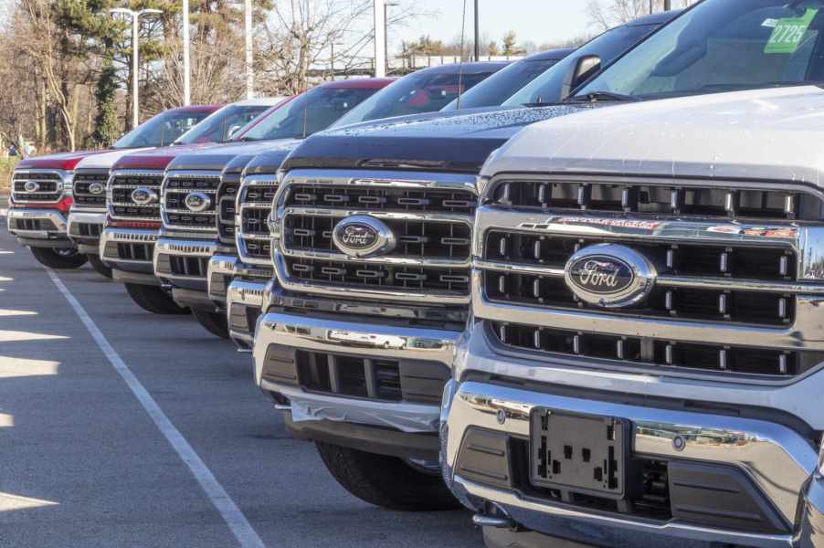 Ford trucks parked in close left front grille view at a dealership