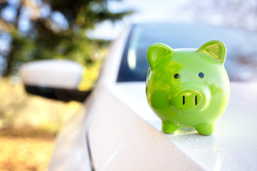 Green piggy bank sitting on car hood representation of an auto loan