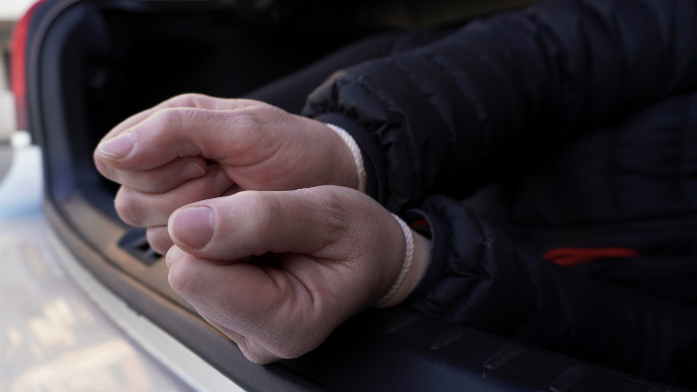 A man with his hands tied up in the trunk of a car