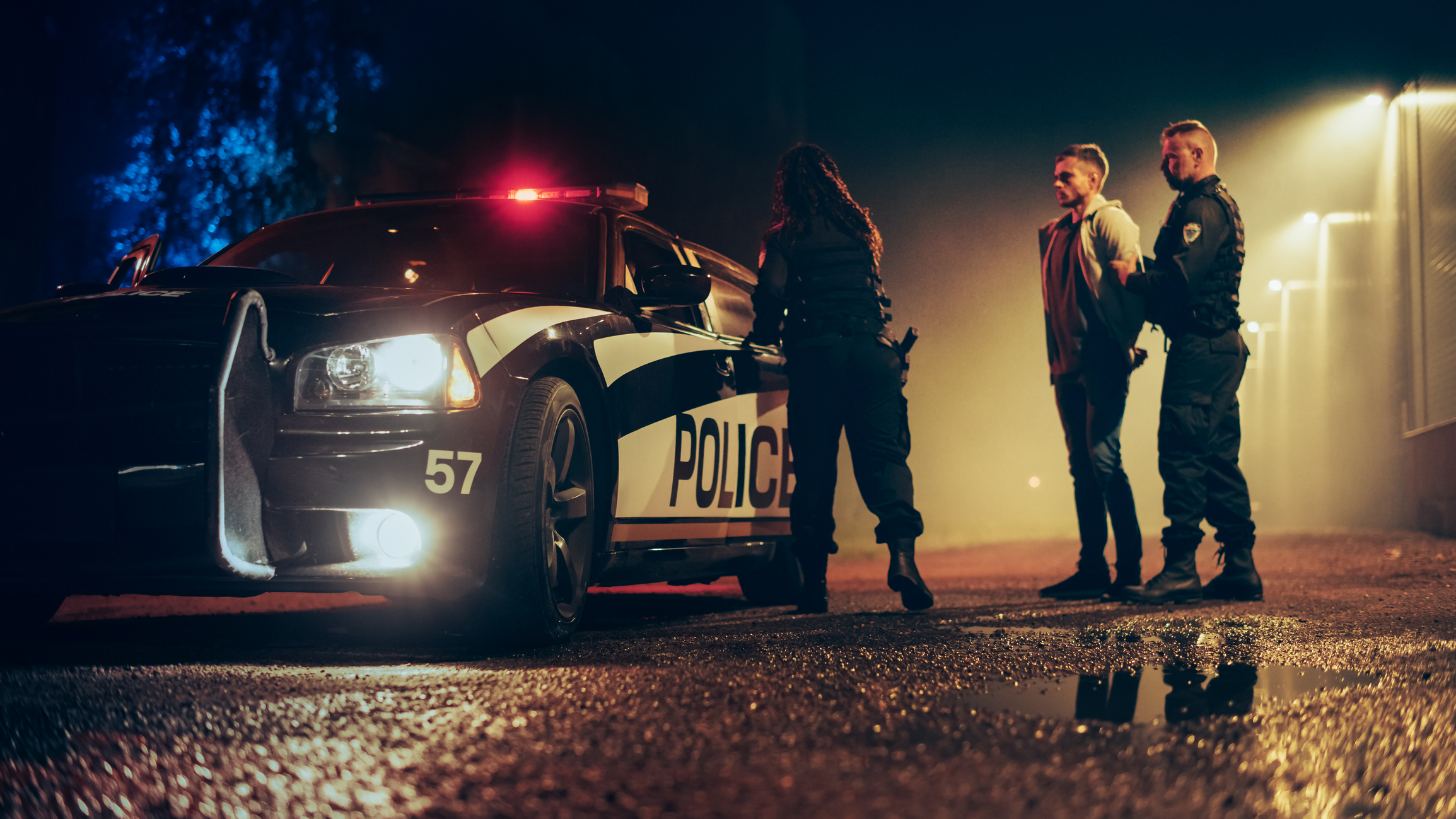 Two police officers arresting a man at night 