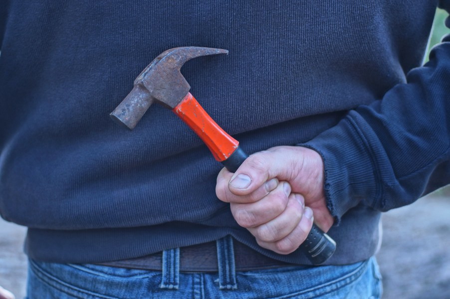 A man holding a hammer behind his back