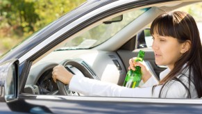 A woman drinking a beer while driving