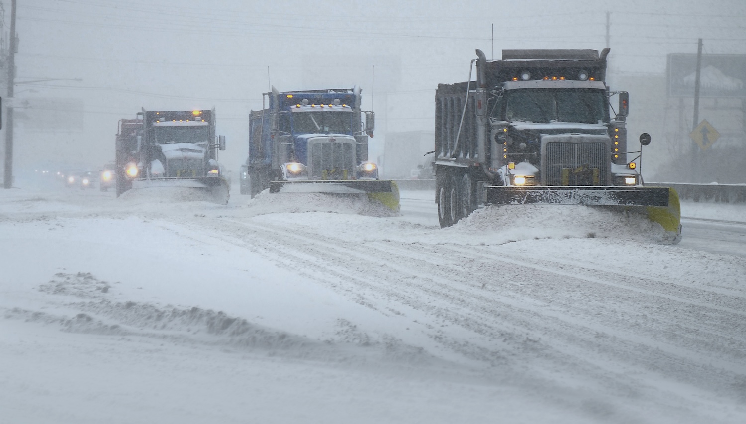 Snowplows clearing the road in a blizzard