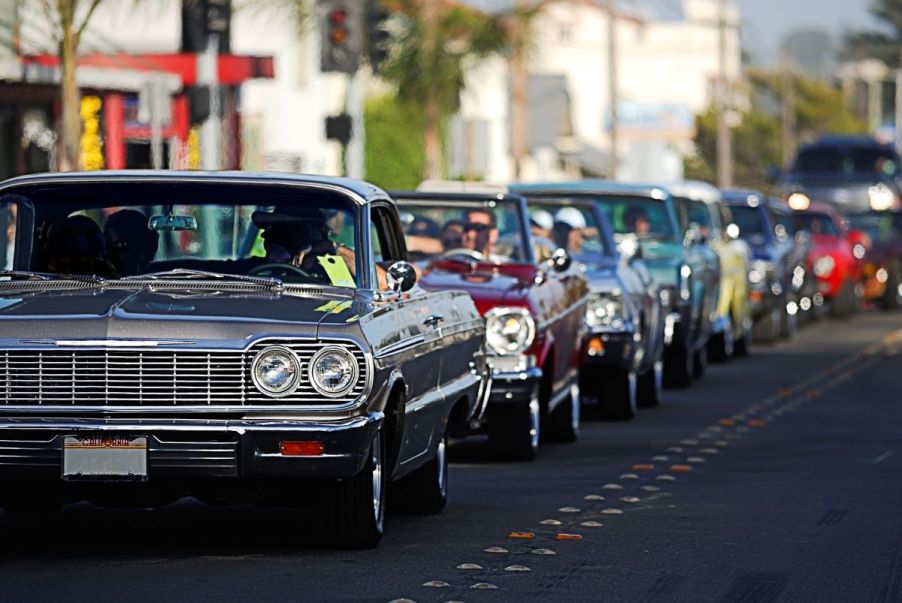 A group of lowrider cars heading to a car show