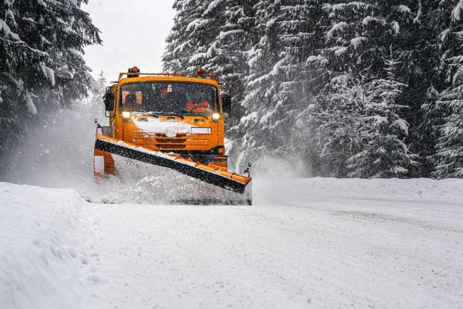 A snow plow removing snow on a snowy road