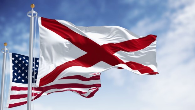 Alabama state flag and the U.S. national flag, a blue sky in the background.