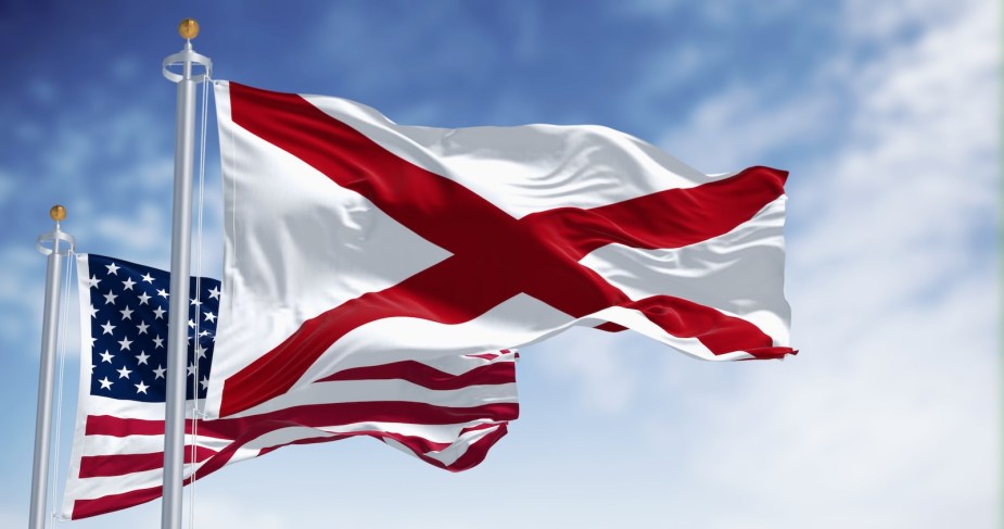 Alabama state flag and the U.S. national flag, a blue sky in the background.