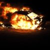 A car fire sends flames and smoke into the air.