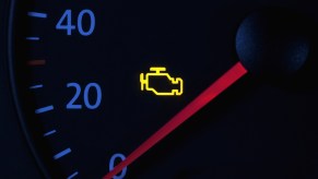 Bright yellow Check Engine Light in the speedometer on the dashboard of a car.