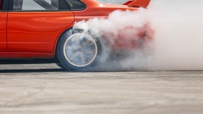 Smoke coming off the tires of a red race car doing burnouts.