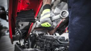 A mechanic holding a wrench in close view of his gloved hand