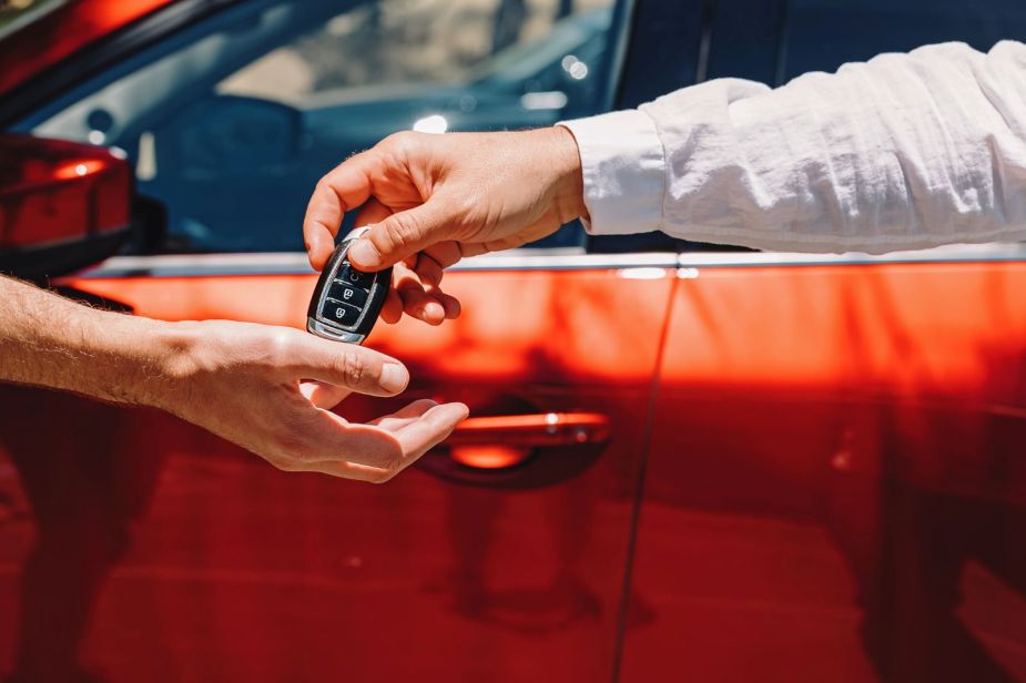 Two men exchanging a car key fob, insinuating the sale of a car