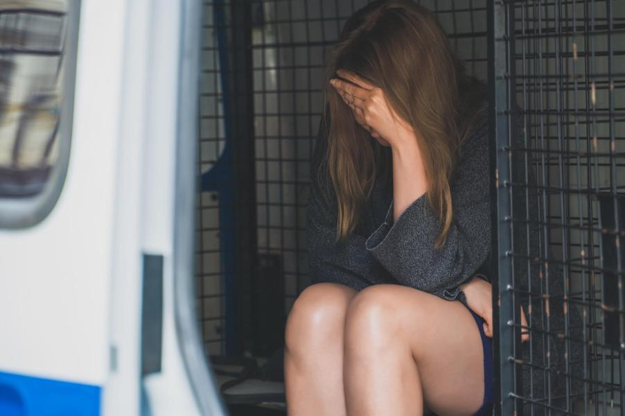 A woman in a police vehicle following a hit-and-run arrest.