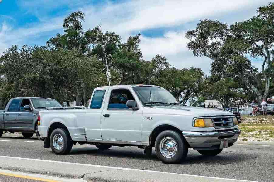 Vintage Ford Ranger pickup truck at a car show, in front of an F-150