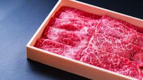 Wooden box of raw beef steaks.
