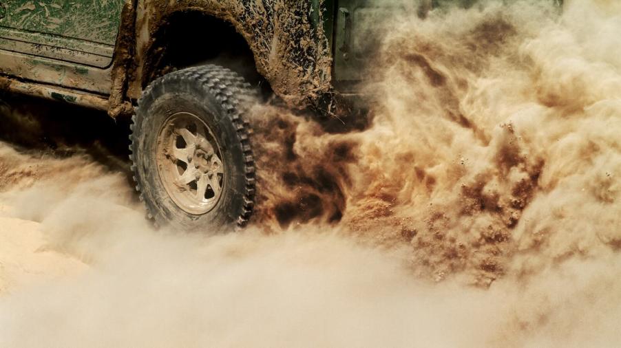 Tire of a Jeep Wrangler SUV kicking up a dust cloud running on steam power.
