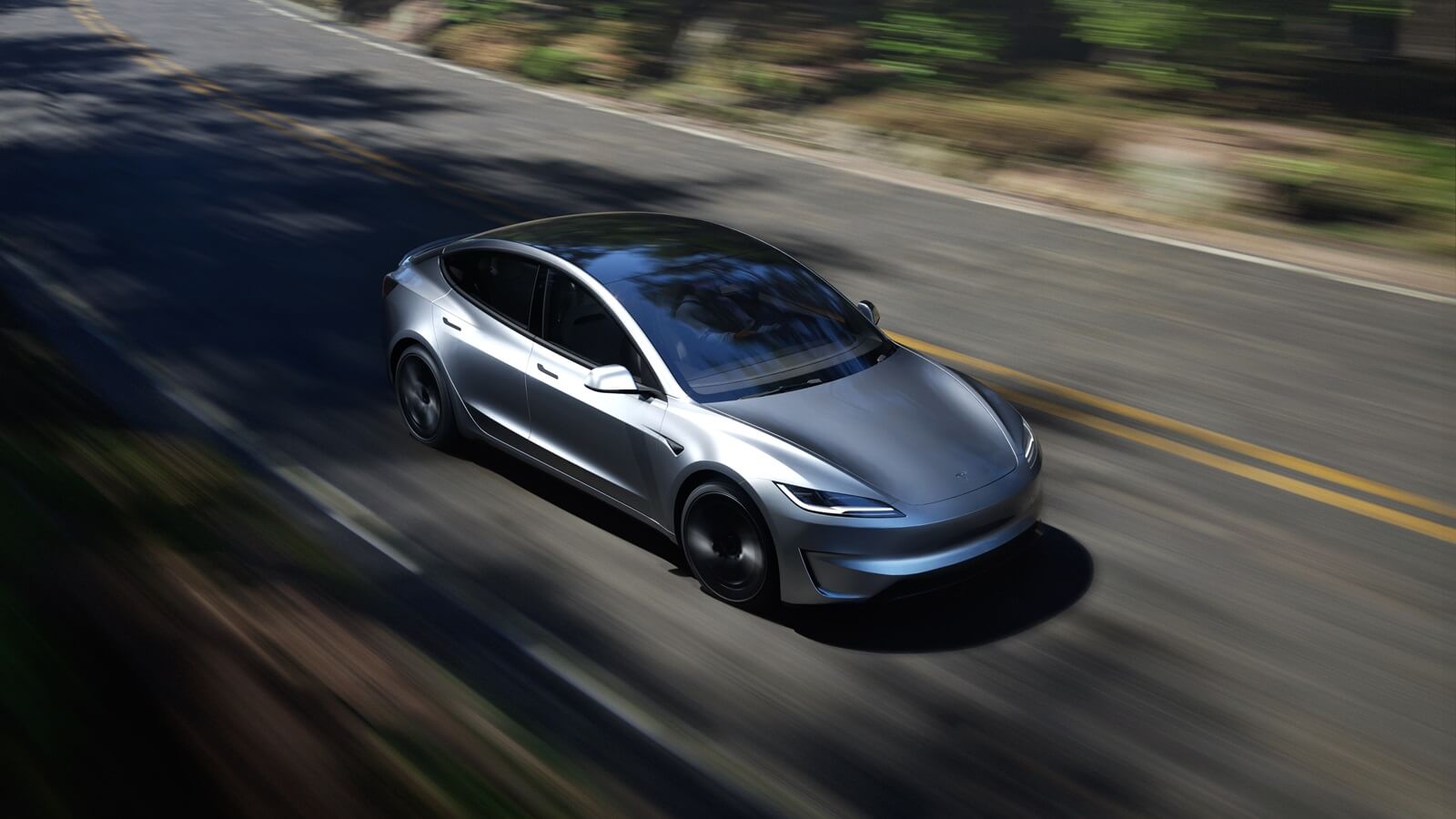 A 2025 Tesla Model 3 Performance drives on an empty road.