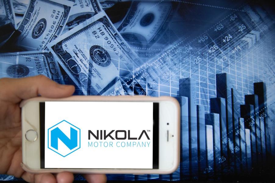 The logo of the Nikola startup displayed on a smartphone, with cash and graphs in the background.