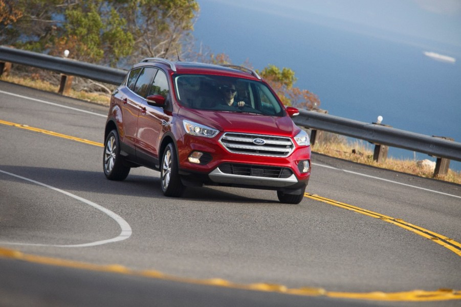 A red Ford Escape driving on a curved freeway near water