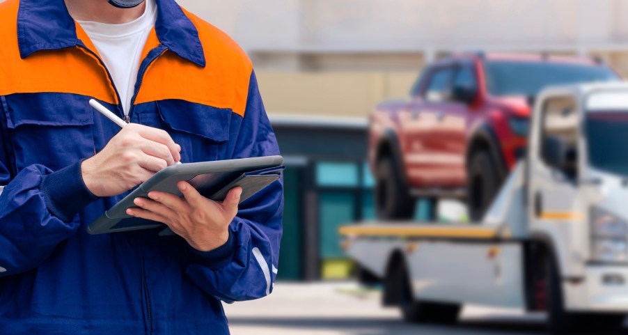 A man with a clipboard near a tow truck