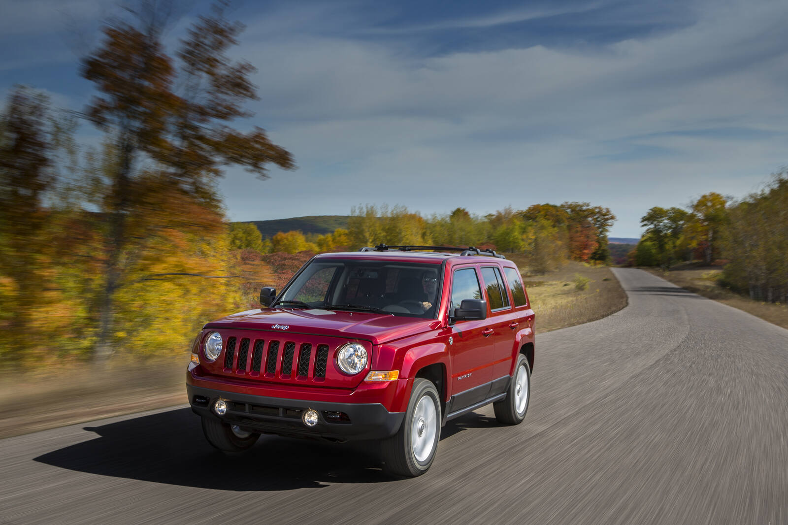 A red 2016 Jeep Patriot driving in left front angle view