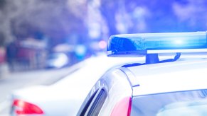 Police cruisier lights in close rear view with silver car crossing in front