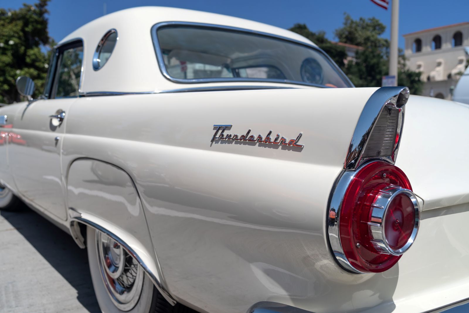 The rear end of a classic Ford Thunderbird in the parking lot of a repair shop