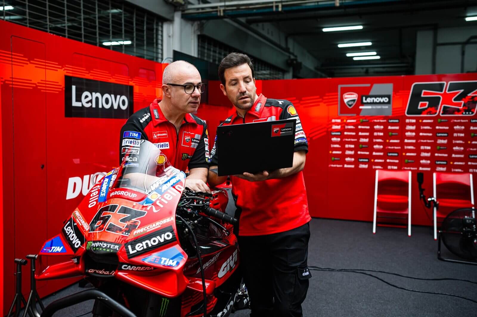 A set of team members work on a Desmosedici GP25 bike. 