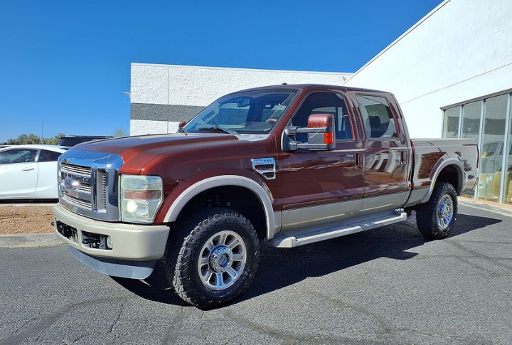 A maroon Ford F-350 Super Duty parked in front of a dealership