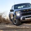 A 2024 Ford F-150 Raptor off-roading on sand in front view