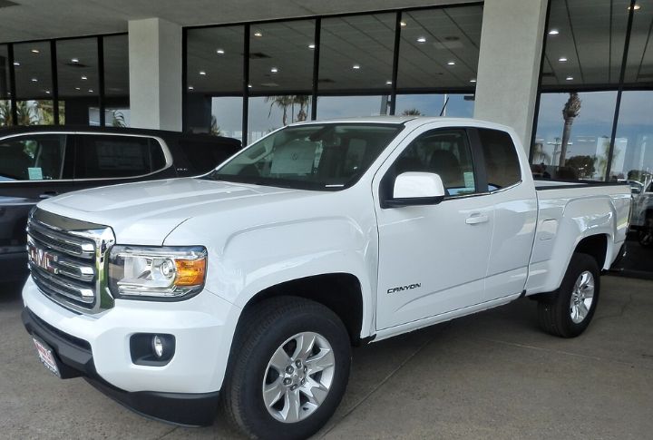 A white GMC Canyon parked in front of a dealership.