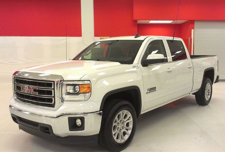 A white GMC Sierra 1500 parked inside a white shop floor