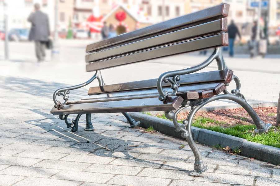 Broken wooden bench at San Francisco bus stop, a man walking away in the background.