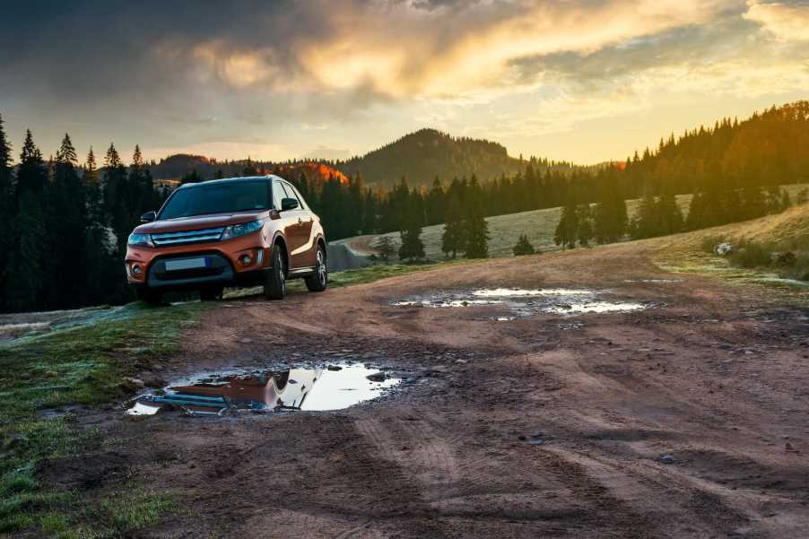 Crossover SUV parked on a dirt off-roading lane after bottoming out on a rock, for an inspection.