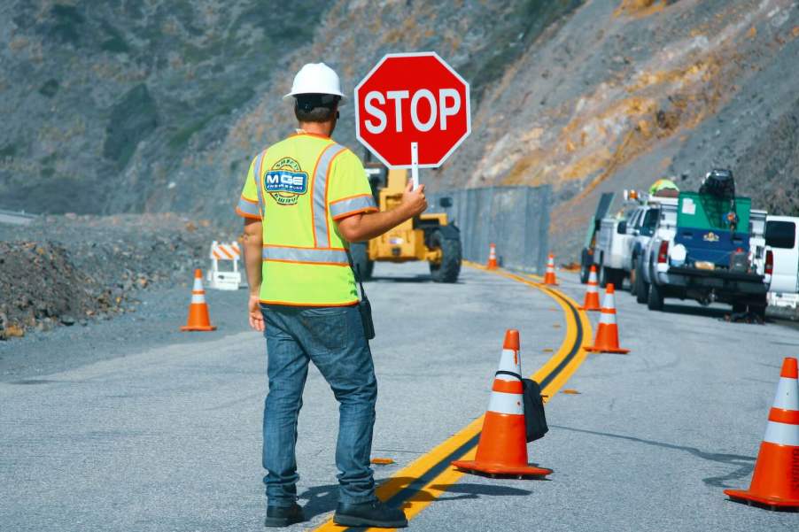 Flagger holding a stop sign stands at a construction site.