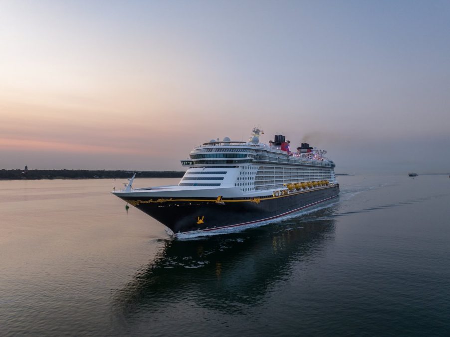 Cruise ship on the ocean at sunset, shore visible in the background.