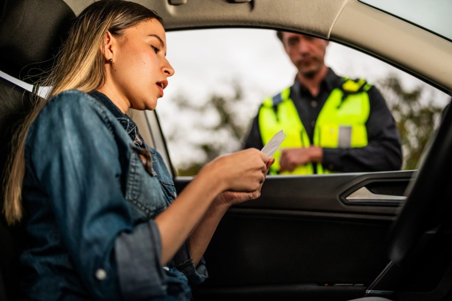 Albert Dolan stands outside a woman's car, impersonating a police officer during a traffic stop.