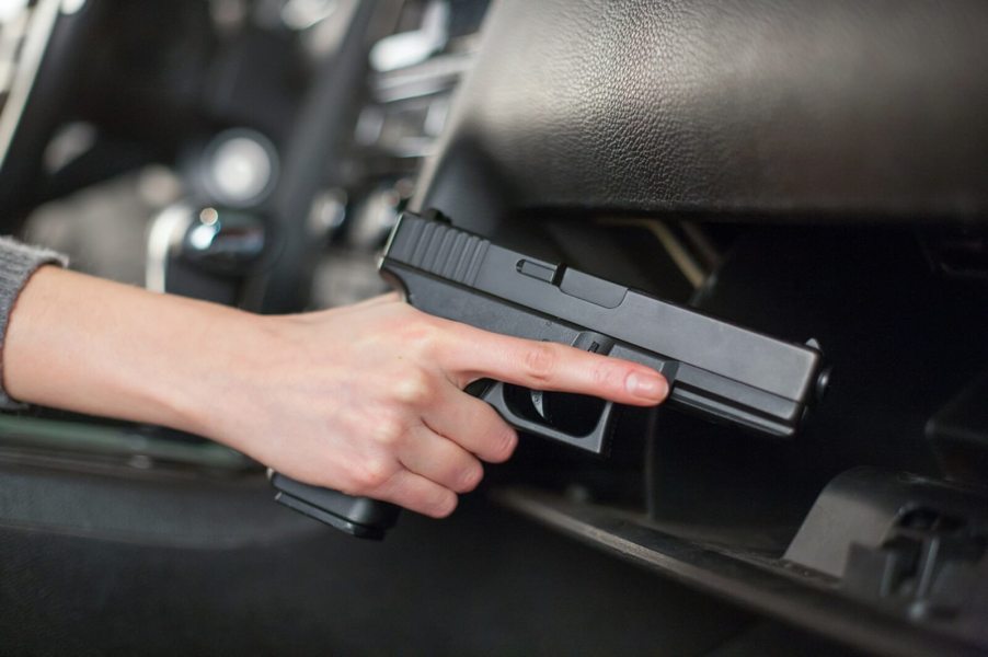 A car thief reaches for a gun, a replica Glock handgun, in a glove box.