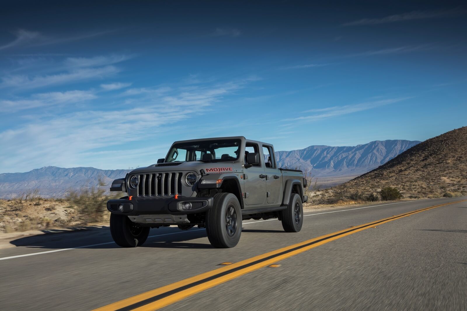 A Jeep Gladiator driving on a wide open road.