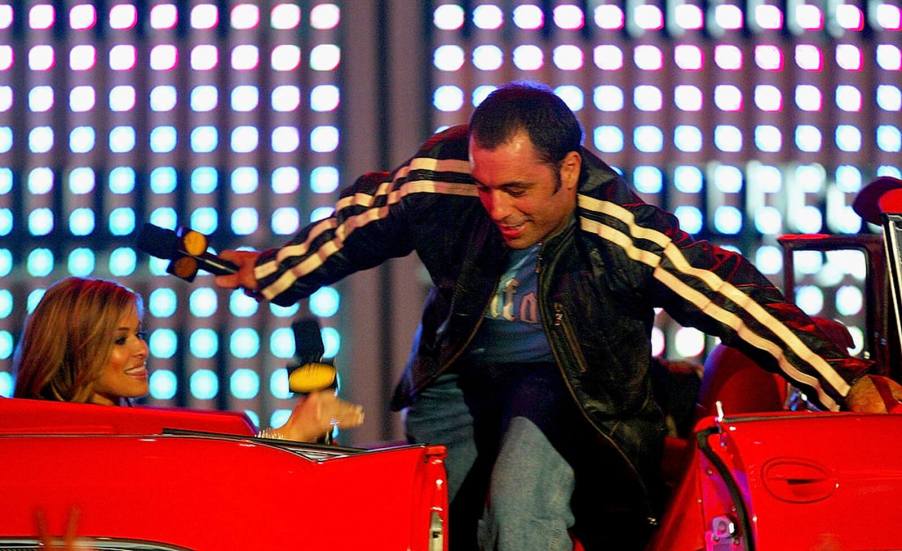 Joe Rogan, who has a unique car collection, climbs out of a car on stage.