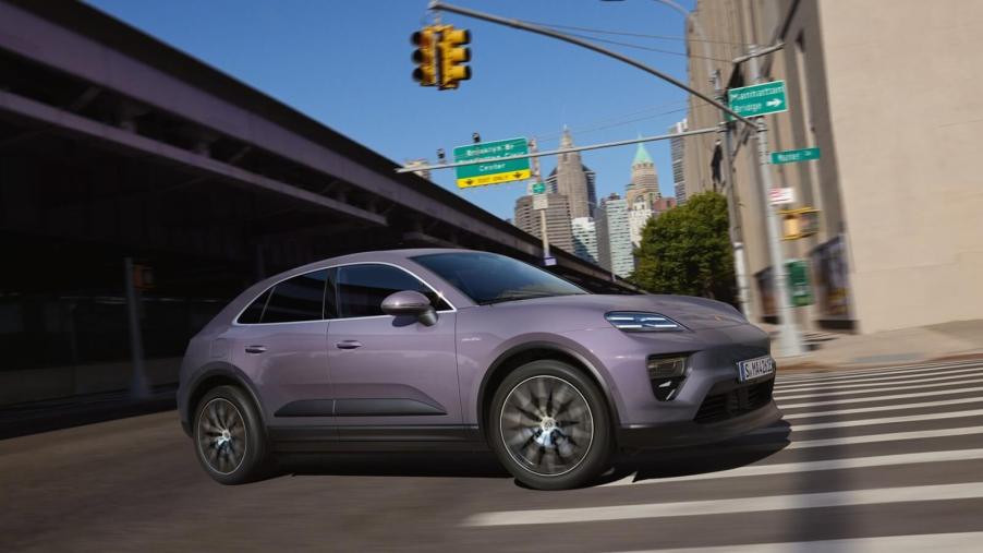 A Porsche Macan EV takes a corner on a city street.