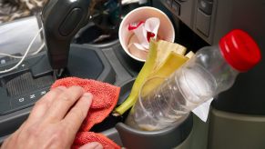 Hand cleaning the messy center console inside a car, hiding a winning lottery ticket.