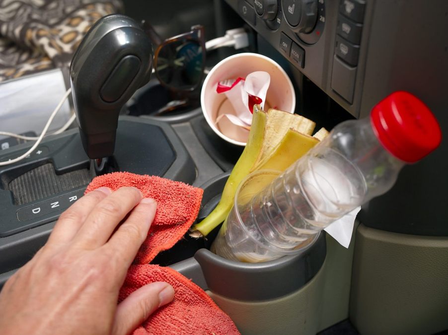 Hand cleaning the messy center console inside a car, hiding a winning lottery ticket.