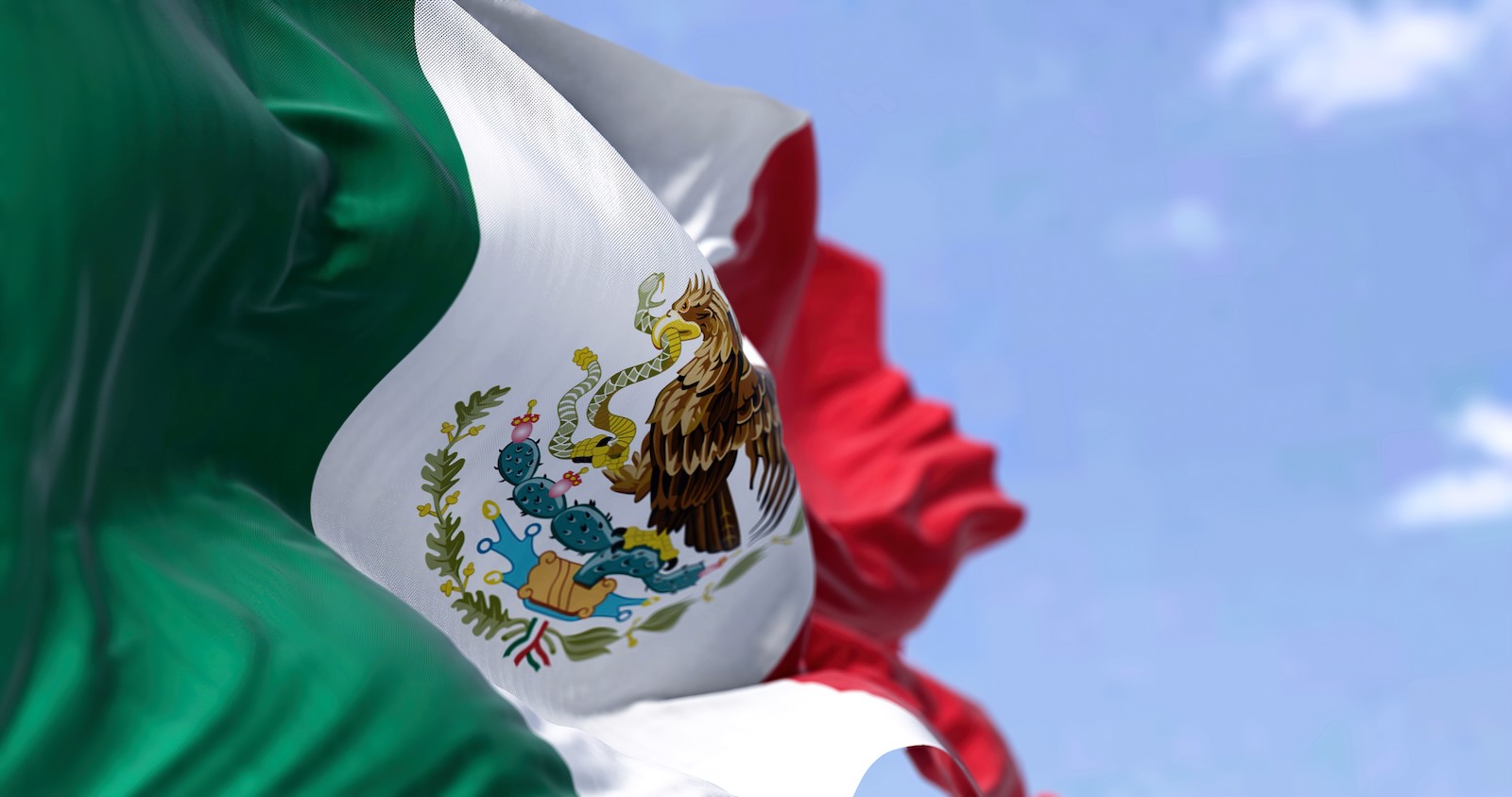 The Mexican national flag over the Saltillo plant where stellantis builds ram trucks in Mexico, a blue sky in the background.