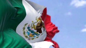 The Mexican national flag over the Saltillo plant where stellantis builds ram trucks in Mexico, a blue sky in the background.