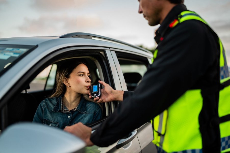 Police officer administers roadside breathalyzer test to a driver.