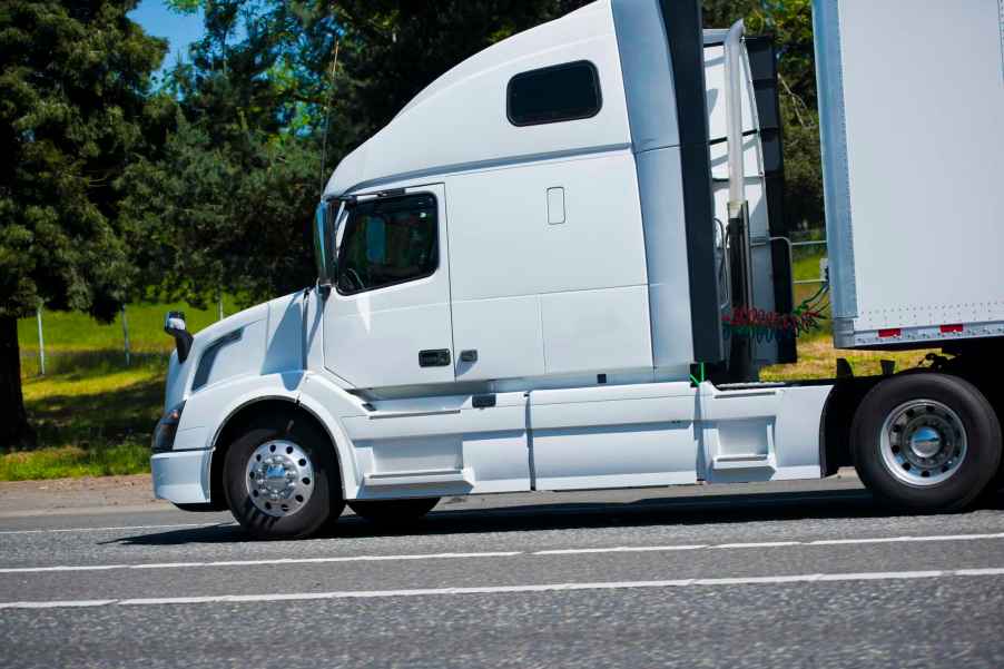 White semi truck with a high window in its cab for a sleeper bunk.